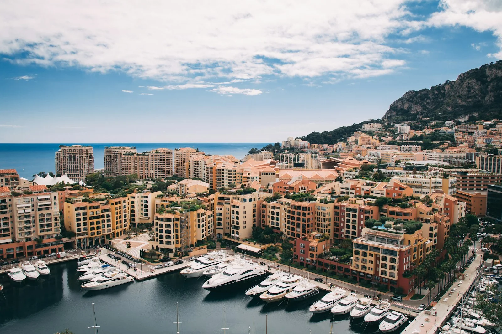 Port de Monaco vu d’en haut, yachts aux quais et immeubles au pied des collines.