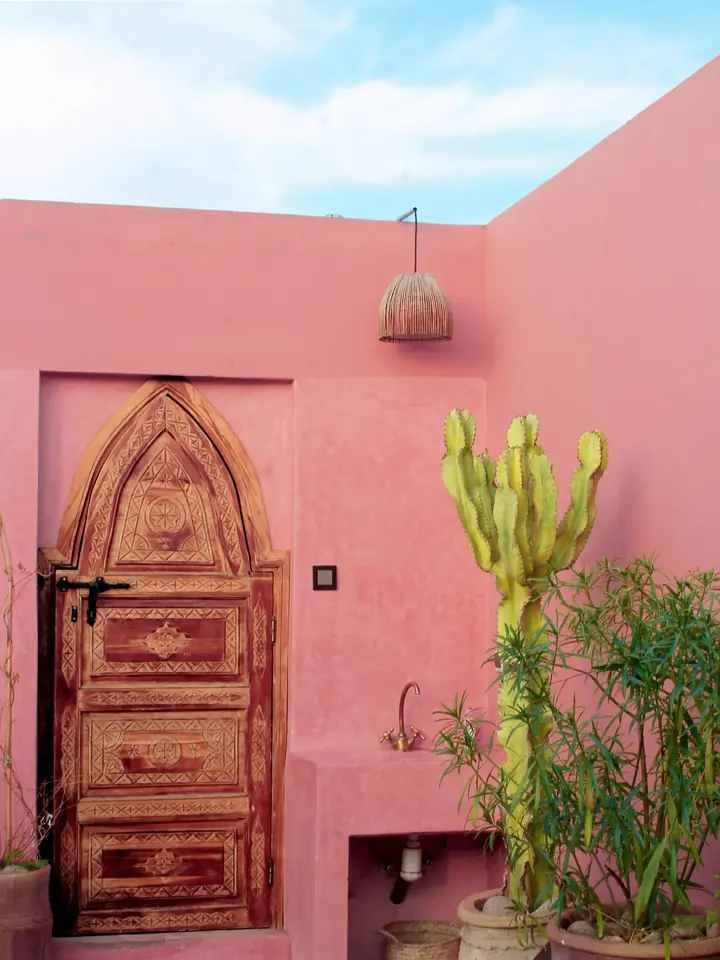 Porte sculptée et patio rose d’un riad, médina de Marrakech