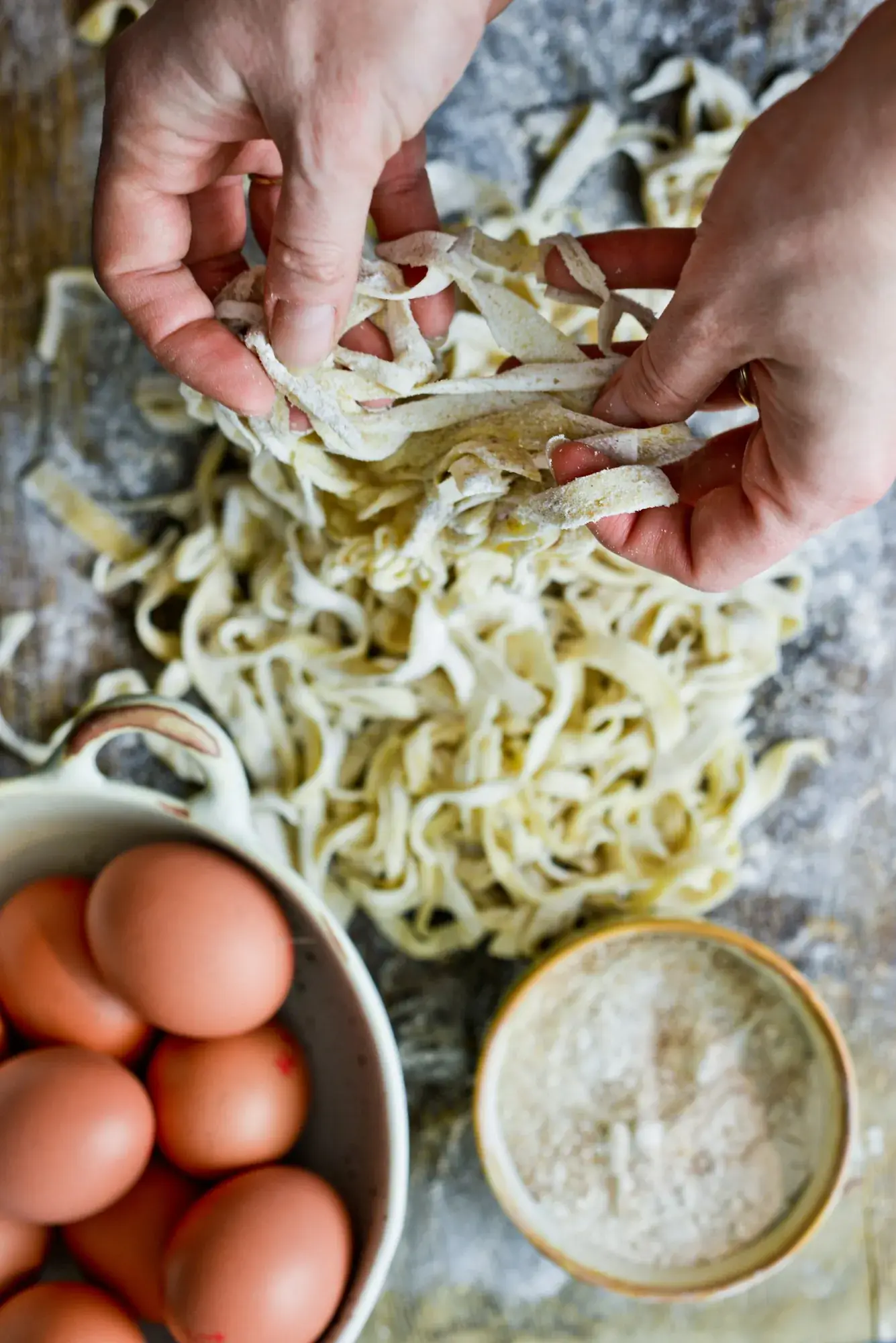 Pâtes fraîches coupées à la main, œufs et farine sur la table