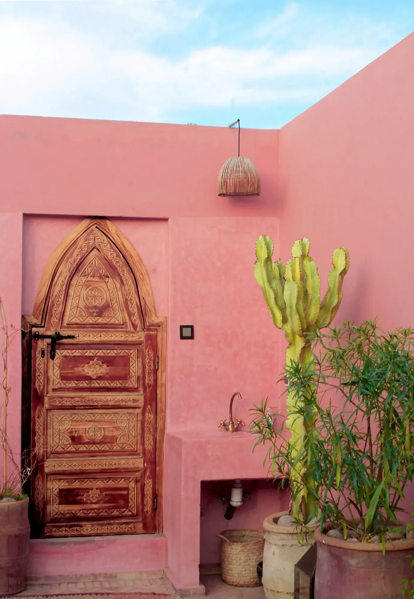 Porte sculptée et patio rose d'un riad, médina de Marrakech