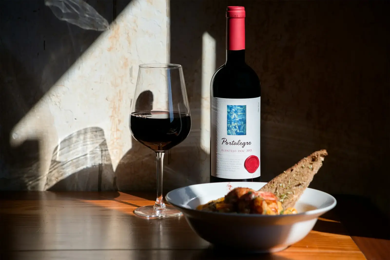 Vin rouge portugais, verre et pain sur une table au soleil
